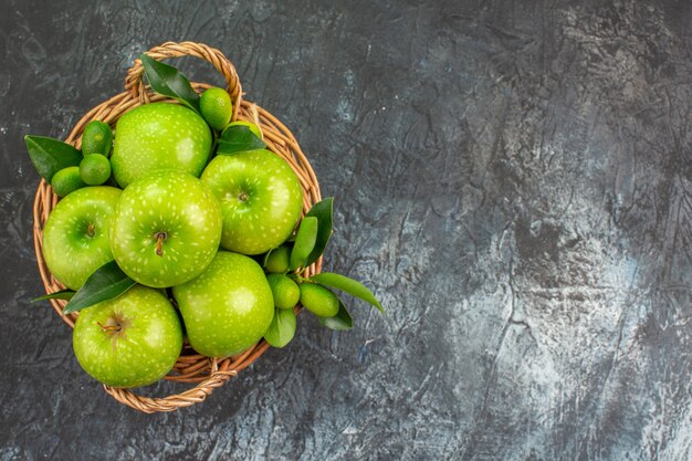 Vista cercana superior manzanas las apetitosas manzanas verdes con hojas en la canasta de madera