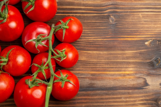 Vista cercana superior tomates rojos verduras maduras en el escritorio de madera marrón ensalada roja dieta fresca madura