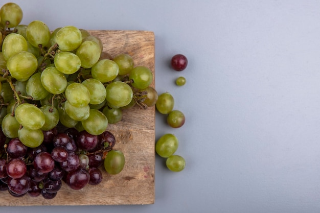 Vista cercana de las uvas en la tabla de cortar sobre fondo gris con espacio de copia