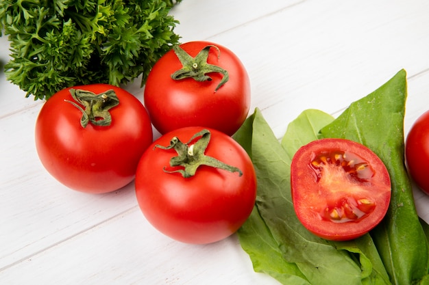 Vista cercana de verduras como espinacas de tomate y cilantro en mesa de madera