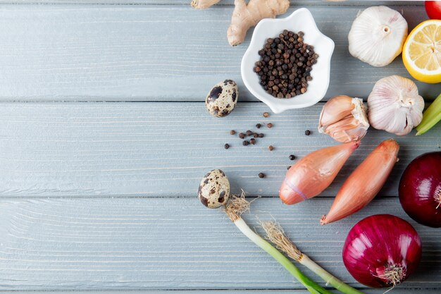 Vista cercana de verduras como huevo cebolla ajo con limón y pimienta negra sobre fondo de madera con espacio de copia