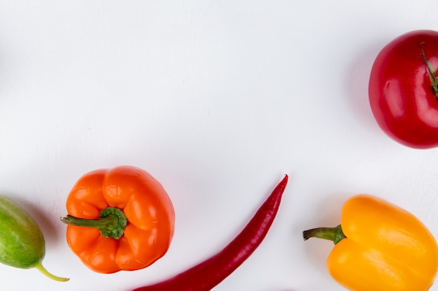 Vista cercana de verduras como pimiento pepino en mesa blanca con espacio de copia