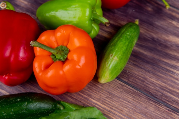 Vista cercana de verduras como pimiento y pepino en mesa de madera