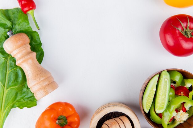 Vista cercana de verduras como tomate pimiento con sal de ensalada de verduras y dejar en la mesa blanca con espacio de copia