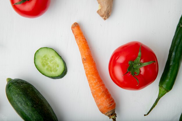 Vista cercana de verduras como zanahoria, pepino, tomate y pimiento sobre fondo blanco.