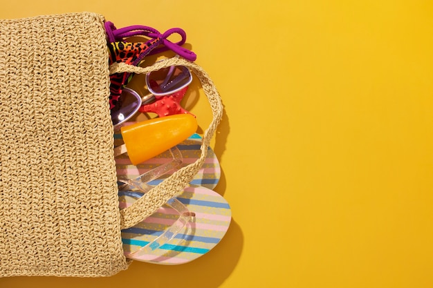 Foto gratuita vista de chanclas con esenciales de verano en bolsa.