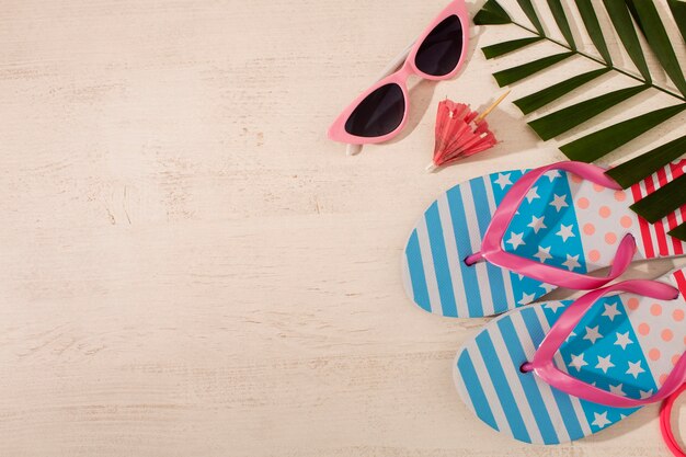 Vista de chanclas con esenciales de verano y gafas de sol.