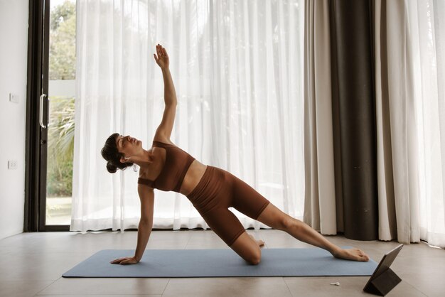 Vista completa de deportistas haciendo yoga atractivo en casa con la mano arriba