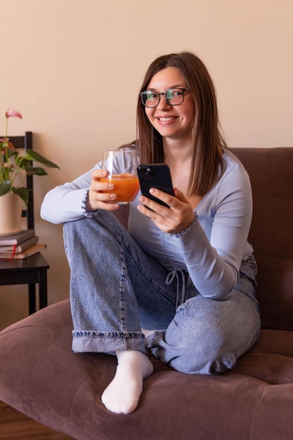 Vista completa de la hermosa mujer sonriendo a la cámara y relajándose en casa con fresco