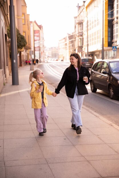 Vista completa de madre e hija caminando por la calle y mirándose