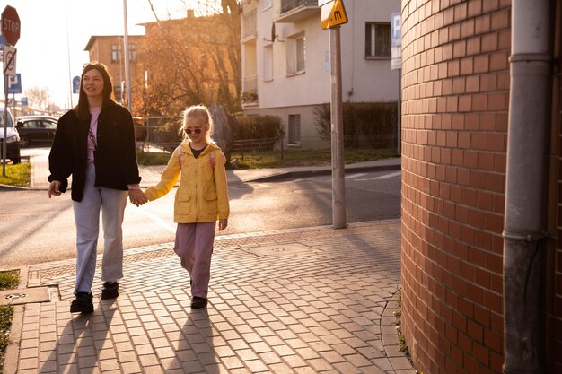 Vista completa de mamá feliz y su hija pequeña al aire libre