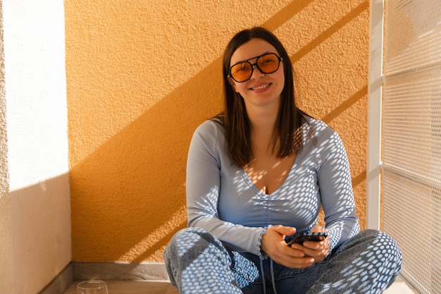 Vista completa de una mujer atractiva con gafas de sol amarillas sonriendo a la cámara