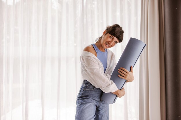 Vista completa de mujer con colchoneta de fitness