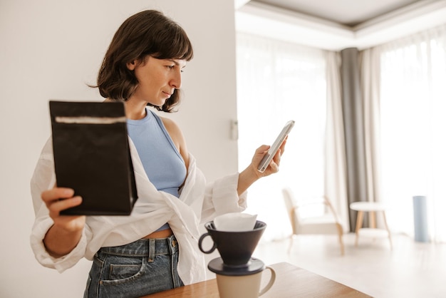 Vista completa de la mujer con equipo de café y lectura de información.