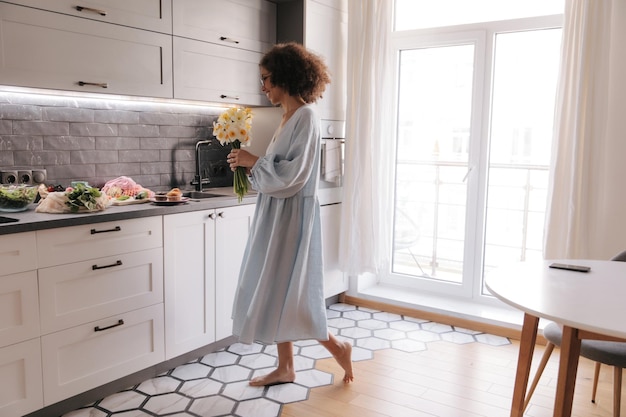 Vista completa de mujer feliz con flores en casa