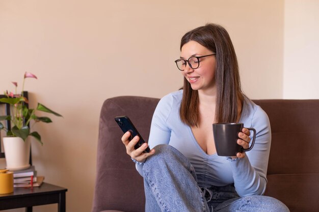 Vista completa de la mujer sentada en casa mira el teléfono