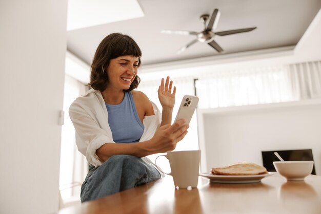 Vista completa de mujer sonriente con taza de café y panqueques