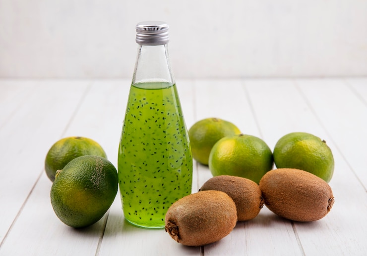 Foto gratuito vista delantera de kiwi con botella de jugo y mandarinas en la pared blanca