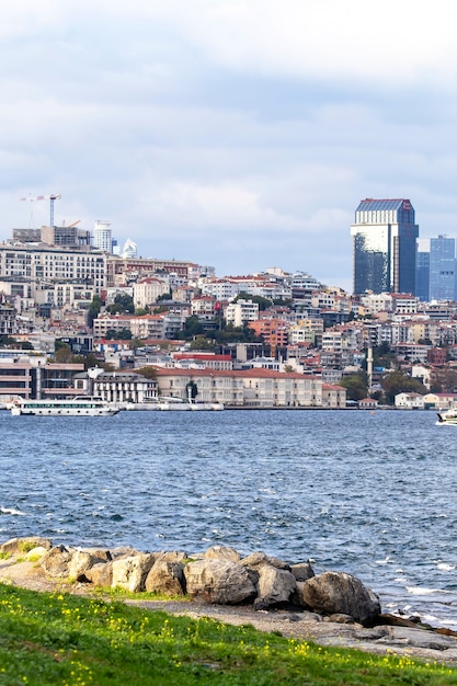 Vista de un distrito con edificios residenciales y modernos en Estambul, Estrecho del Bósforo con barcos, gente descansando en la orilla, Turquía