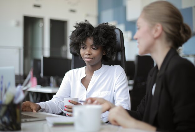 Vista de dos compañeras de trabajo sentadas una al lado de la otra en un concepto de oficina: rivalidad, compañera de trabajo