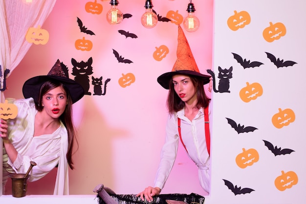 Vista de dos niñas de halloween a través del agujero en la pared blanca. diseño festivo de halloween. las mejores amigas celebran el día de acción de gracias. espacio de copia de halloween.