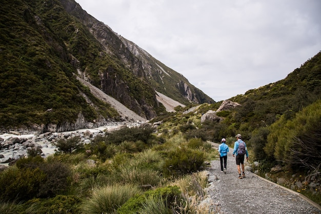 Vista de dos personas caminando en los acantilados cubiertos de árboles con un río entre los acantilados