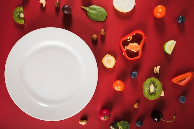 Vista elevada de alimentos crudos frescos con placa sobre fondo rojo