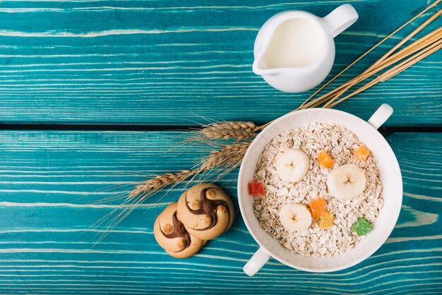 Vista elevada de avena con leche y galletas en la mesa