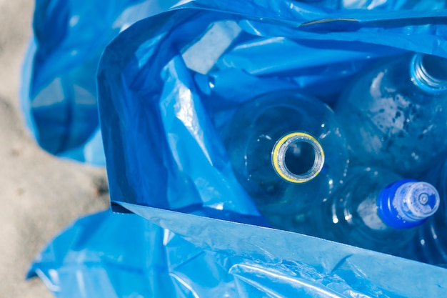 Vista elevada de la bolsa de basura azul de botellas de plástico de desecho