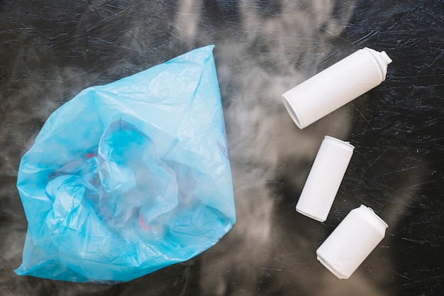 Vista elevada de botellas blancas y bolsa de plástico rodeada de humo