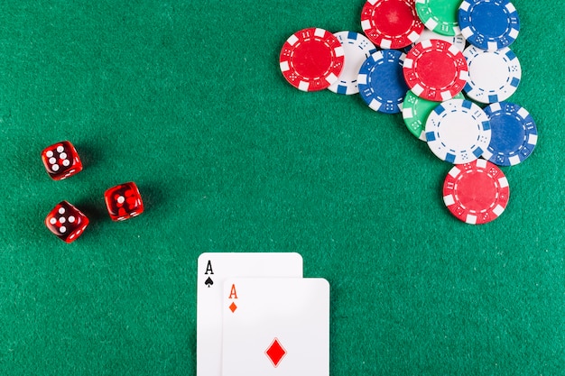 Foto gratuita vista elevada de las cartas del as; dados y fichas en la mesa de poker