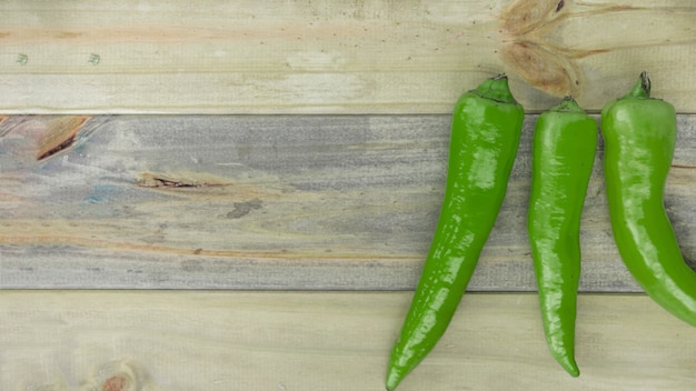 Vista elevada de chiles verdes sobre fondo de madera