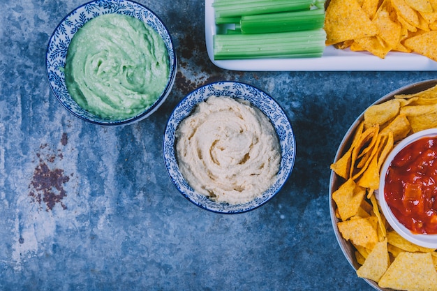 Vista elevada de chips de nachos mexicanos con guacamole y salsa de salsa en un tazón