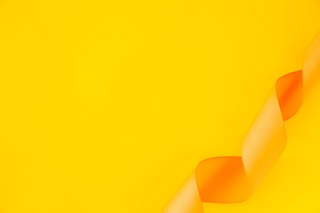 Vista elevada de cinta de raso rizado sobre fondo amarillo