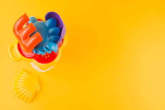 Una vista elevada de coloridos juguetes de plástico sobre fondo amarillo