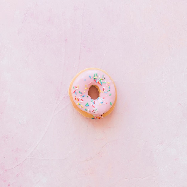 Foto gratuita vista elevada de donut con chispas sobre fondo rosa