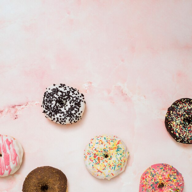 Una vista elevada de donuts al horno en el fondo rosa