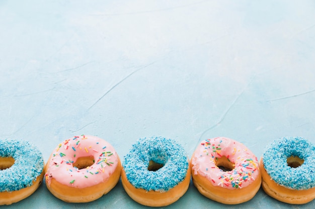 Foto gratuita vista elevada de donuts decorativos sobre fondo azul