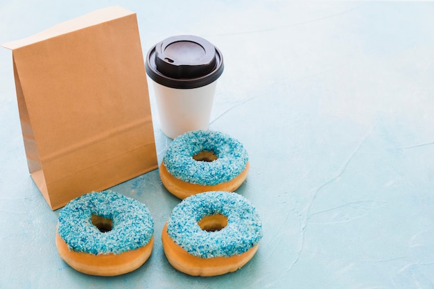 Vista elevada de los donuts; Envase y desecho de taza sobre fondo azul.