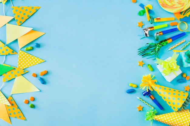 Vista elevada de dulces con accesorios de fiesta sobre fondo azul