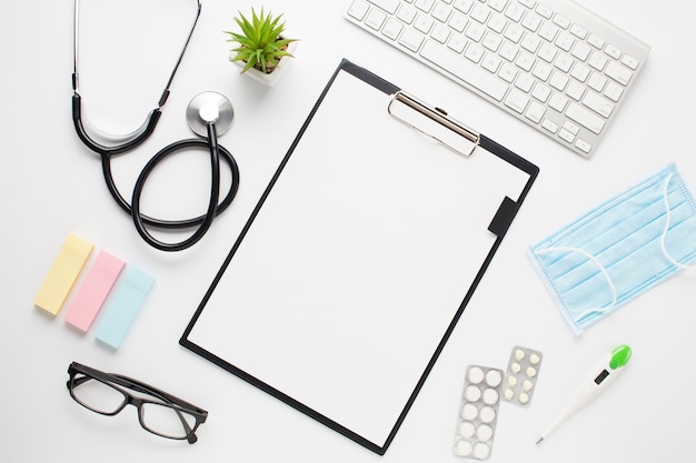 Vista elevada del escritorio del médico con portapapeles y teclado inalámbrico