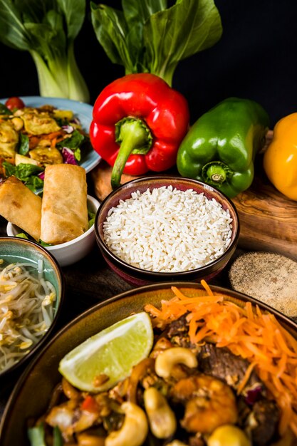 Una vista elevada de fideos con arroz; rollitos de primavera y pimientos