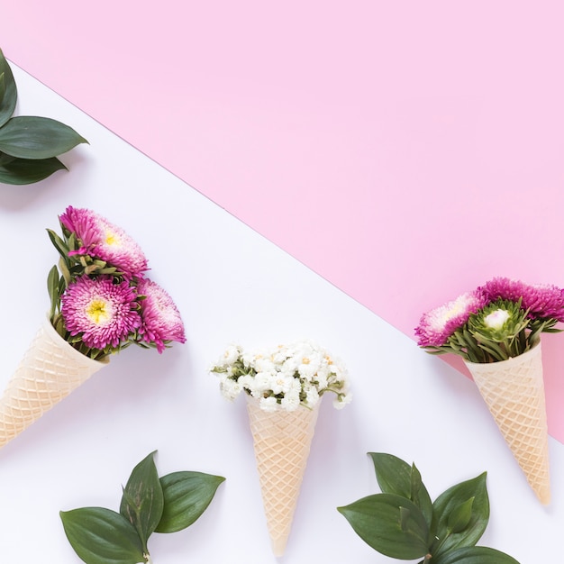 Vista elevada de flores frescas en cono de helado de galleta en doble fondo