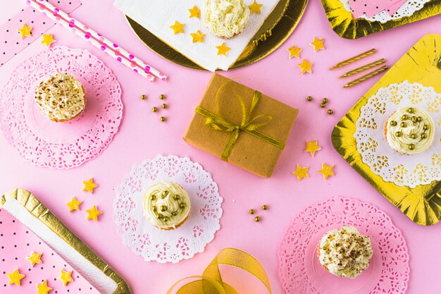 Vista elevada de fondo rosa decorativo con cupcakes y regalo de cumpleaños