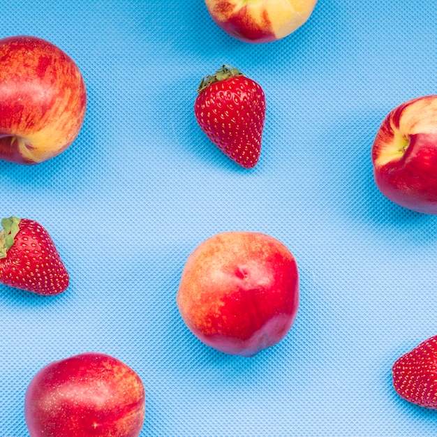 Vista elevada de fresas y manzana sobre fondo azul