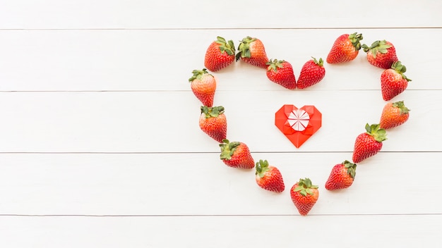 Foto gratuita vista elevada de fresas rojas frescas formando forma de corazón en la superficie de madera