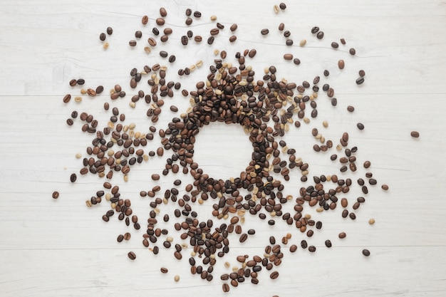 Vista elevada de los granos de café crudos y tostados en el escritorio de madera