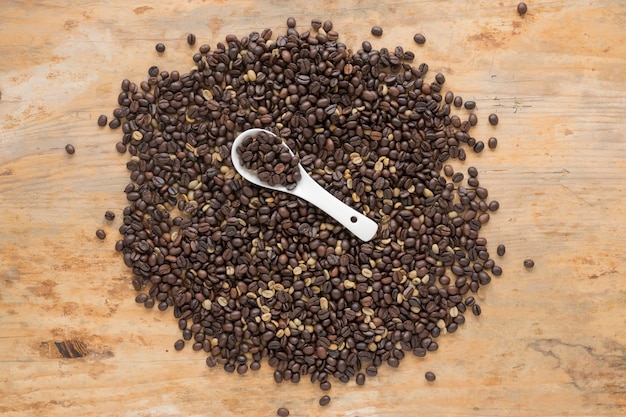 Foto gratuita vista elevada de granos de café con cuchara en mesa de madera