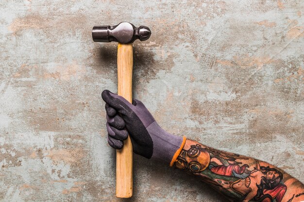 Vista elevada de un hombre que sostiene el martillo en el escritorio de madera
