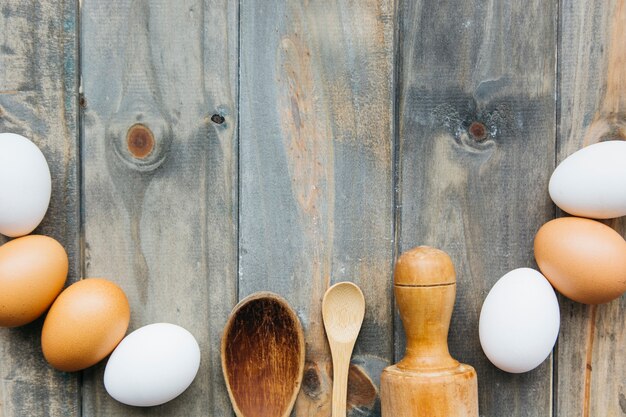 Vista elevada de huevos con rodillo y cuchara sobre fondo de madera